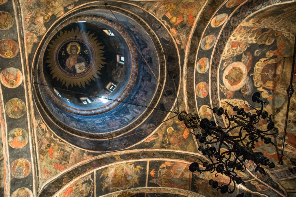 A photo of the magnificent ceiling inside one of Bucharest's old churches. The intricate details and stunning beauty of the ceiling are highlighted in the photo, inviting visitors to step inside and admire the grandeur of these historic buildings.