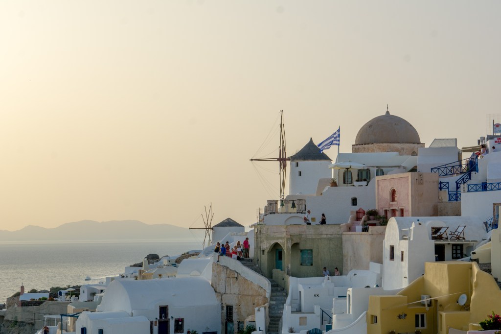 Sunset in Santorini, Greece - a picturesque view of the sea and a village with white houses and blue roofs.