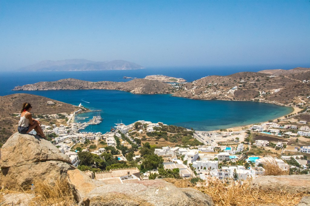 Bianca overlooking the traditional white houses and pristine beaches of Santorini, Greece. Explore the beauty of Santorini with our travel blog.