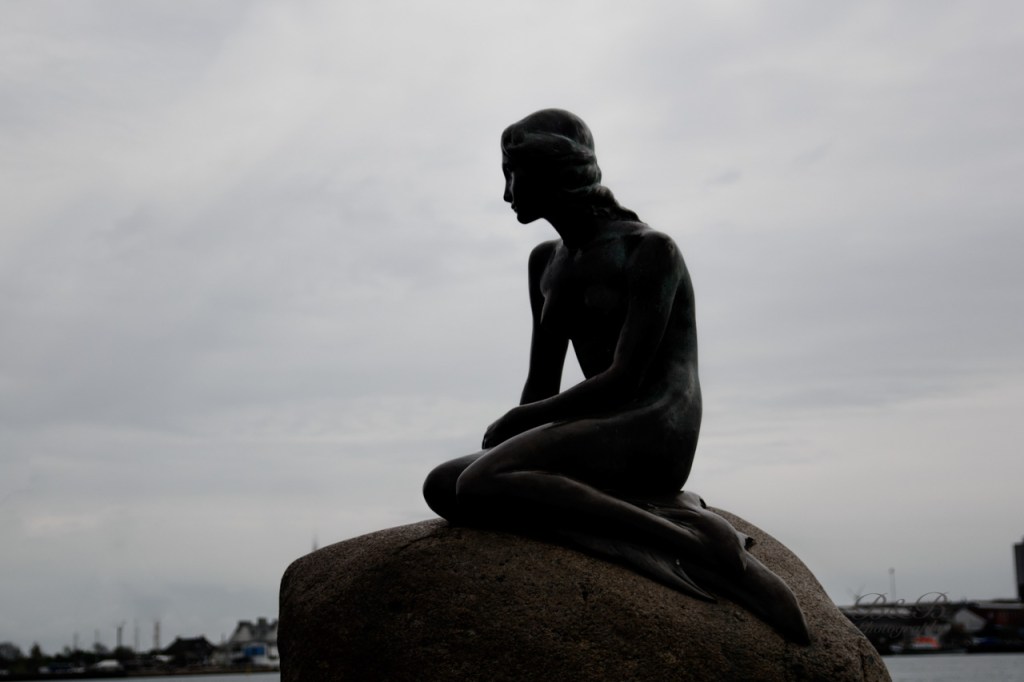 View of the Little Mermaid statue and Kastellet fortress barracks in Copenhagen, Denmark - a picturesque and iconic sightseeing spot.