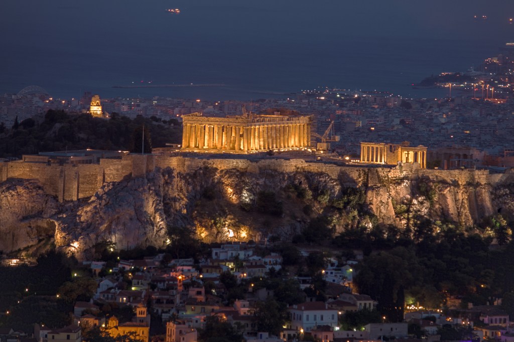 Acropolis lit up at night in Athens, Greece. Discover the magic of Athens at night with our travel blog.