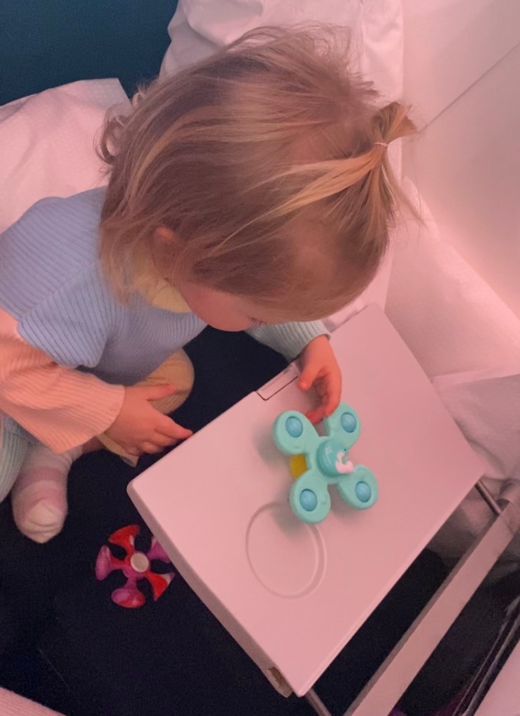 Toddler keeping busy using a fidget spinner on the airplane.