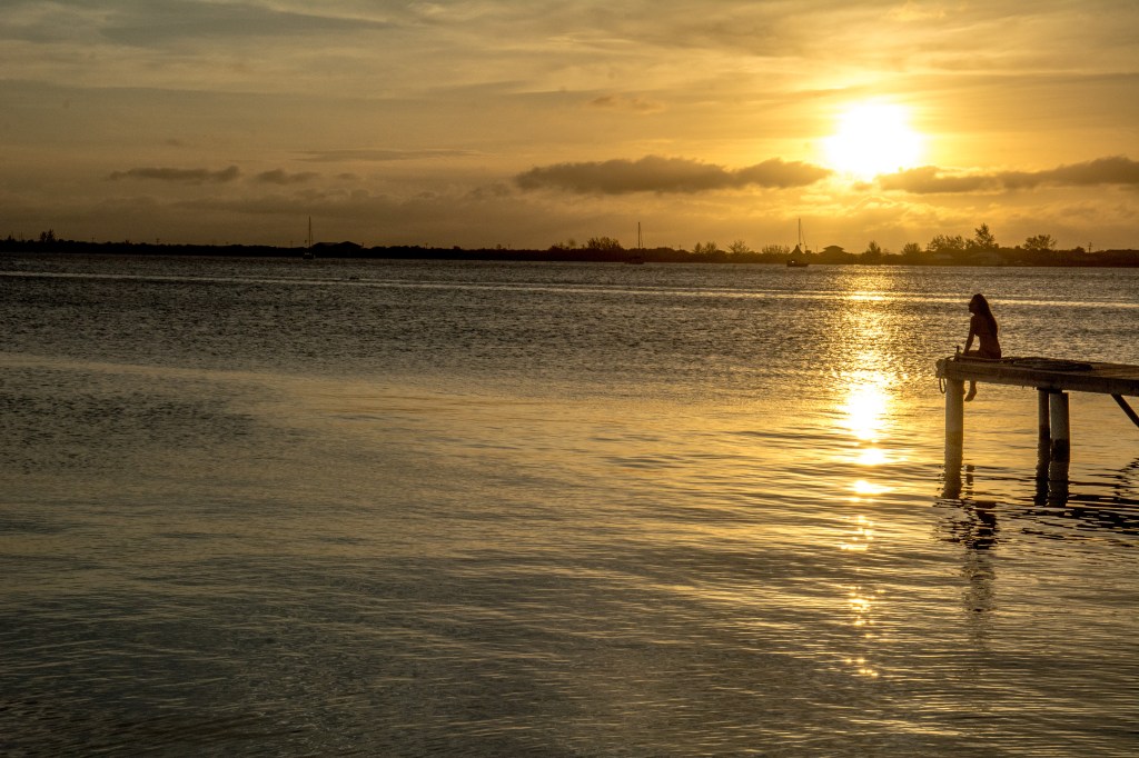 Bianca Relishing a Breathtaking Utila Island Sunset Over the Ocean.