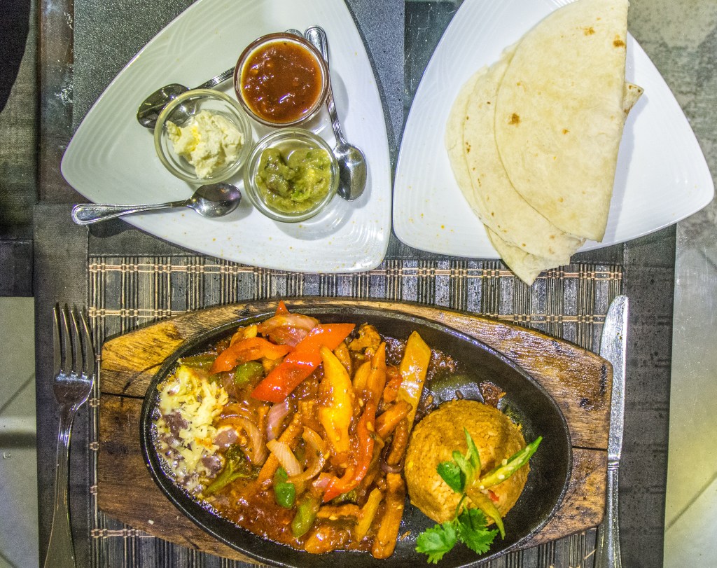 Image showcasing a beachfront restaurant recommended by locals, offering traditional curries and local drinks in a scenic setting.