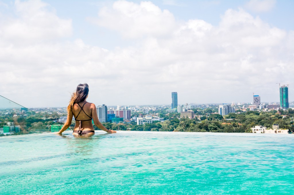 Image of Bianca relaxing in the rooftop swimming pool overlooking Colombo, Sri Lanka, enjoying the serene atmosphere.