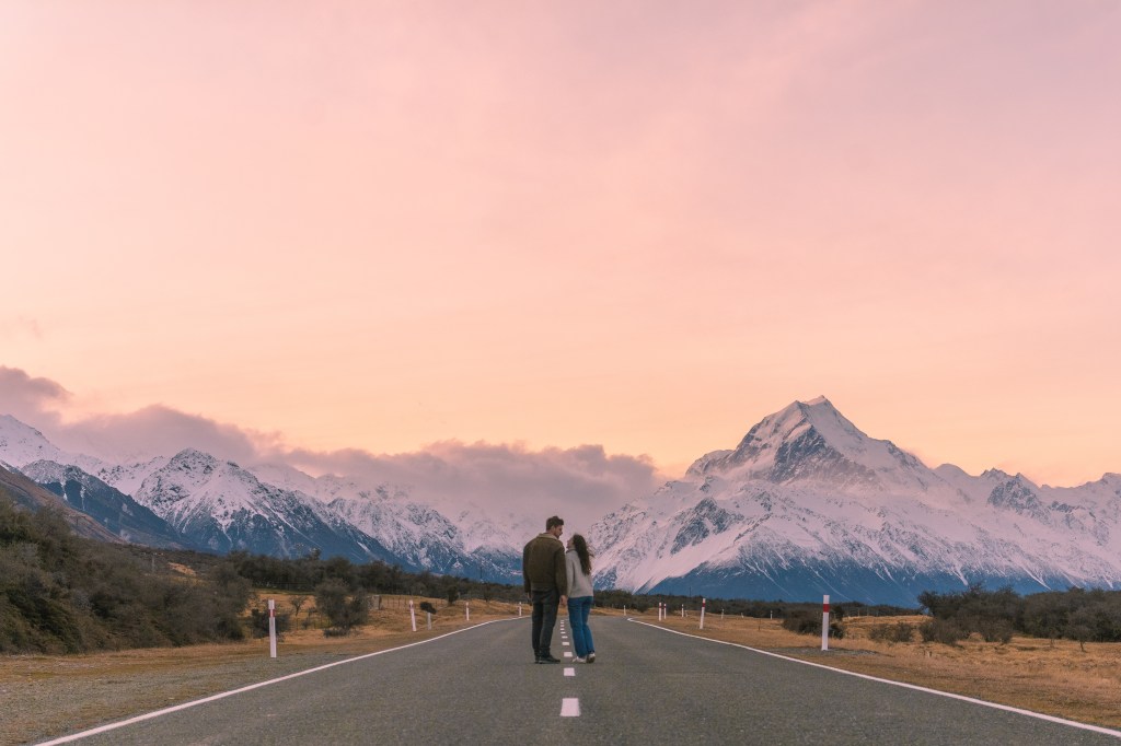 Bianca and Brett captivated by the pastel sunset colors against the stunning mountain range backdrop. Immerse yourself in the magic of nature's canvas in this breathtaking travel moment.