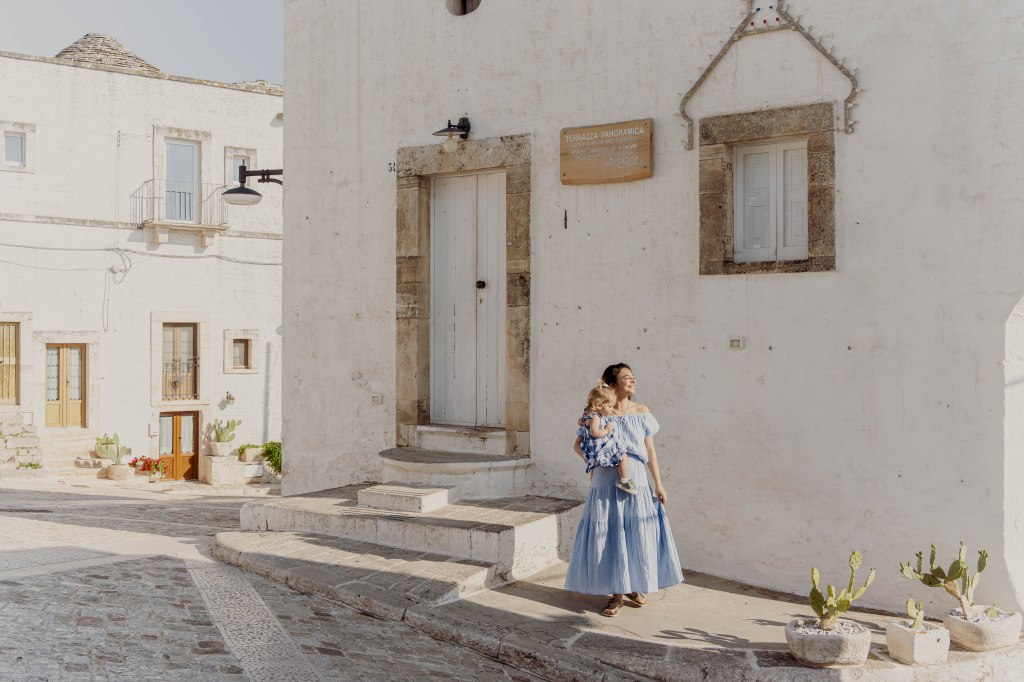 Image of the white-washed buildings lining a street in Alberobello, Italy, showcasing the unique and picturesque architecture of the traditional trulli houses, a UNESCO World Heritage site.