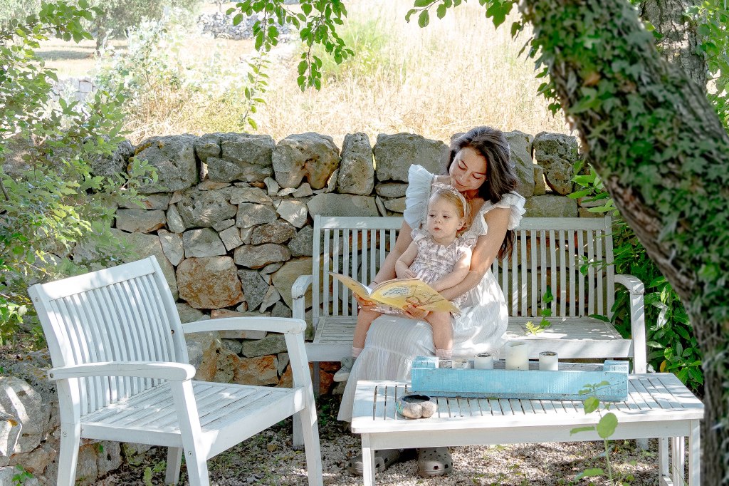 Image of Bianca reading a story to Florence at their Airbnb in Puglia, Italy, a heartwarming moment captured in their cozy and inviting accommodation, offering a glimpse into their family travel experience.