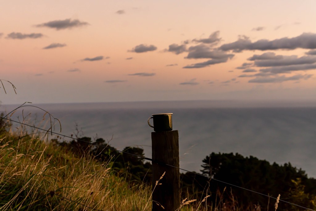 Morning coffee at a remote Unyoked cabin, New Zealand - serene nature escape surrounded by wilderness.