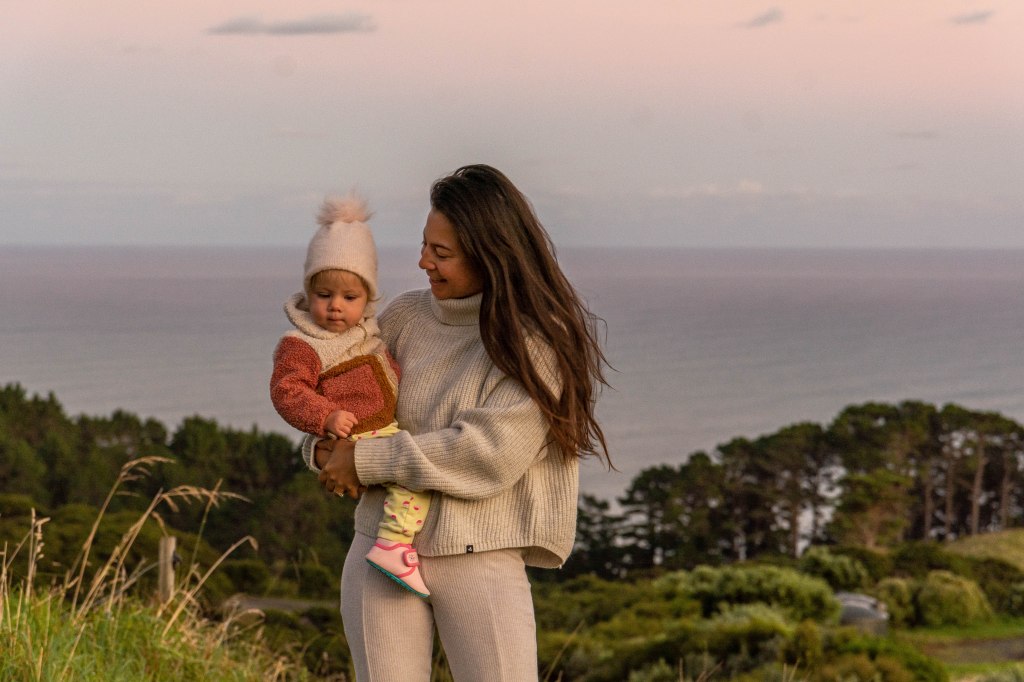 Florence and Bianca watching a beautiful sunrise over the horizon in New Zealand - peaceful morning by the coast.