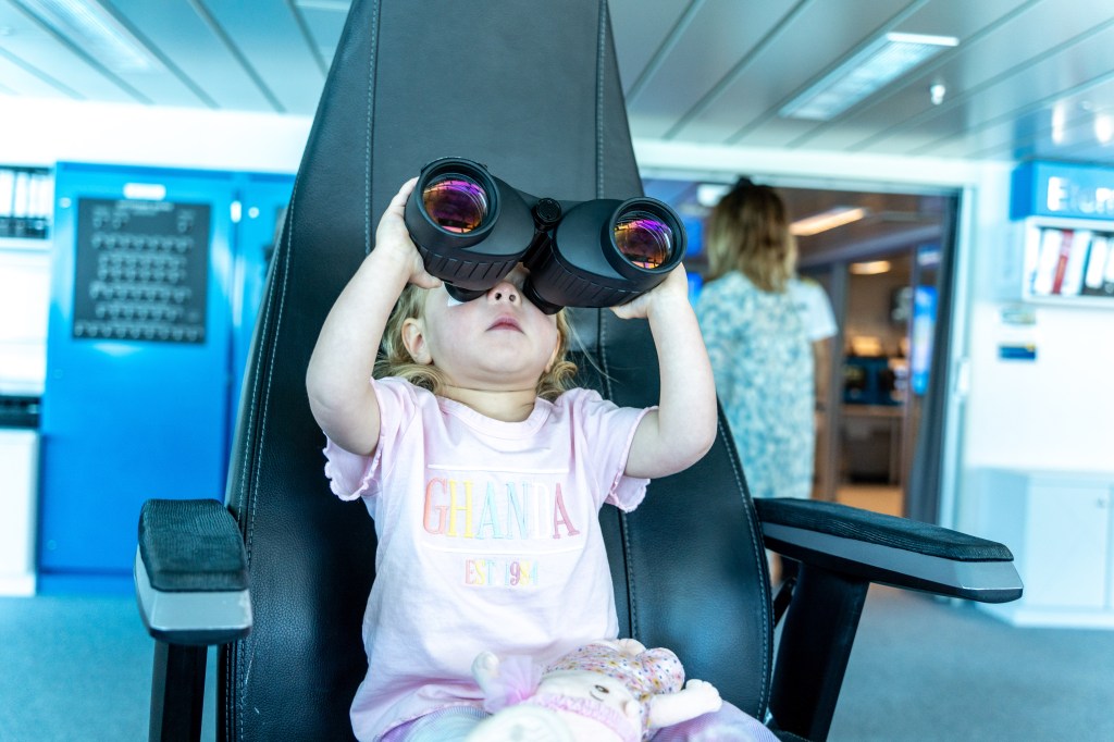 Florence sitting in the captain's seat aboard the Celebrity Edge Cruise during its inaugural New Zealand voyage, enjoying a special family moment.