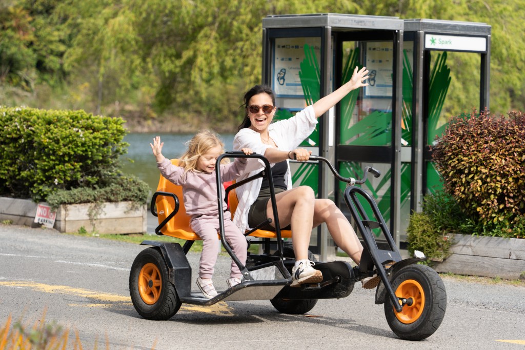 Bianca and Florence riding a two-seater pedal cart at Blue Lake TOP 10 Holiday Park in Rotorua, New Zealand — fun family activity available for hire at this kid-friendly campground.