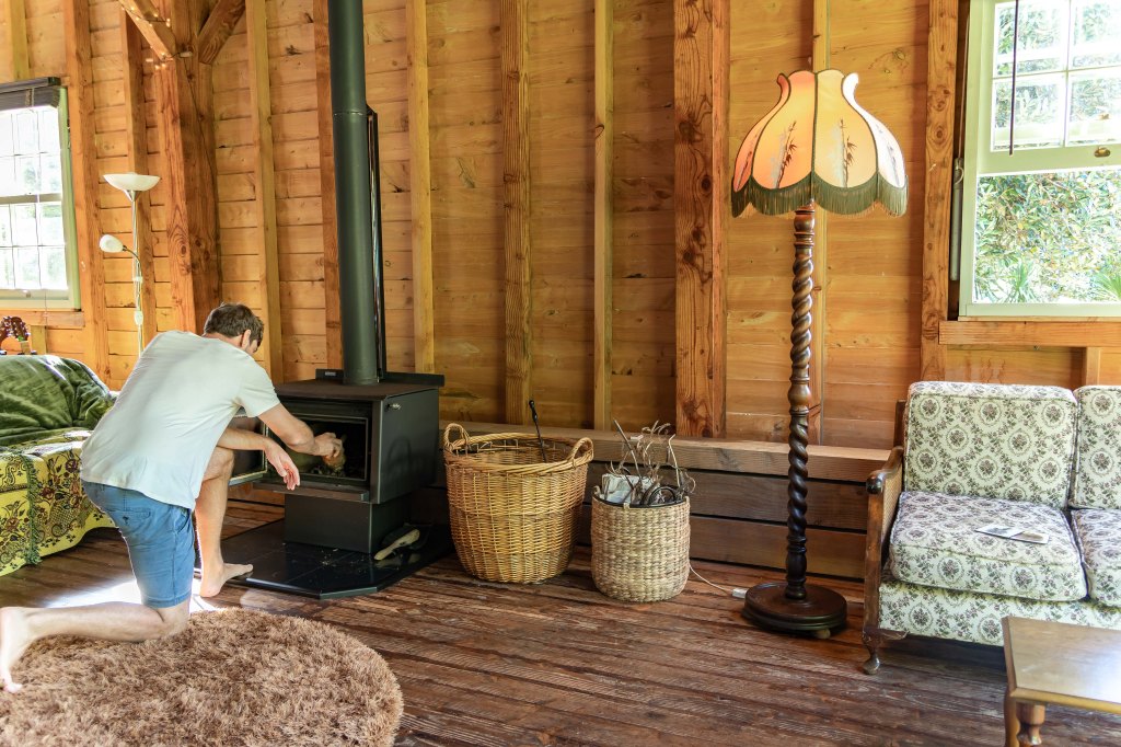 Brett setting the fire pit at Wainui Seaside Glamping during a cozy New Zealand family getaway by the coast.