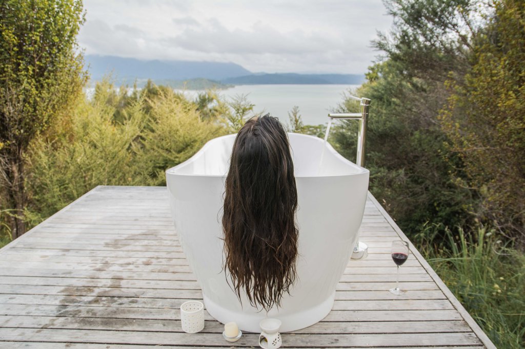Serene outdoor bath with breathtaking views at our Opononi accommodation in New Zealand, perfect for a peaceful nature escape.