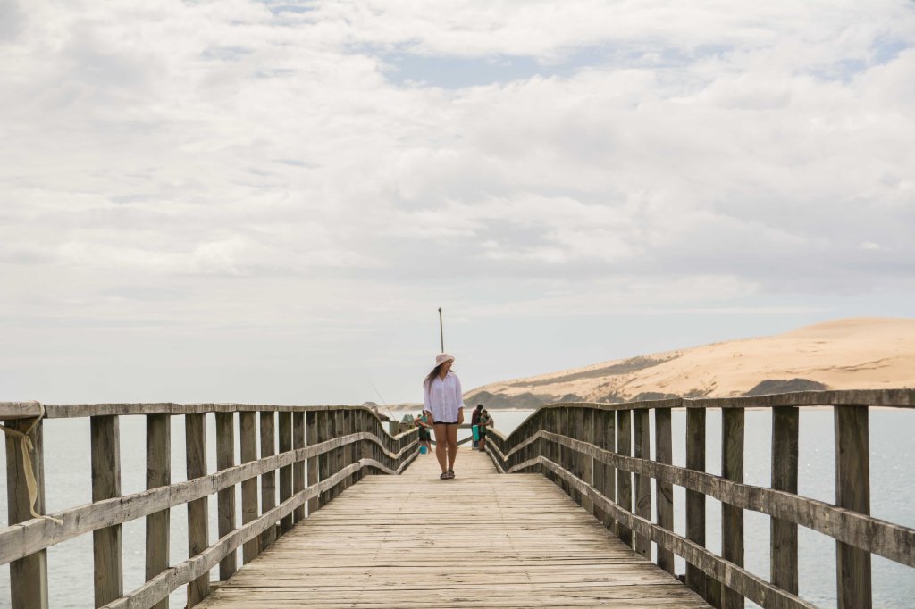 Bianca strolling along the historic Opononi Wharf, enjoying coastal views in Northland, New Zealand.