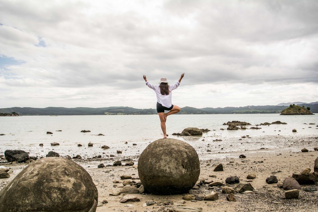 Fun family photo opportunity at the Koutu Boulders in Opononi, New Zealand, featuring unique spherical rock formations along the Hokianga Harbour.