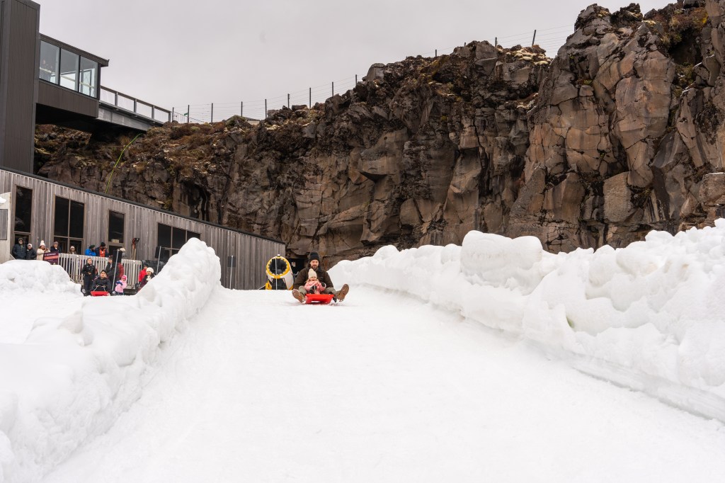 Brett and Florence tobogganing down snowy slopes at Mount Ruapehu, family winter holiday in Tongariro National Park, New Zealand travel blog