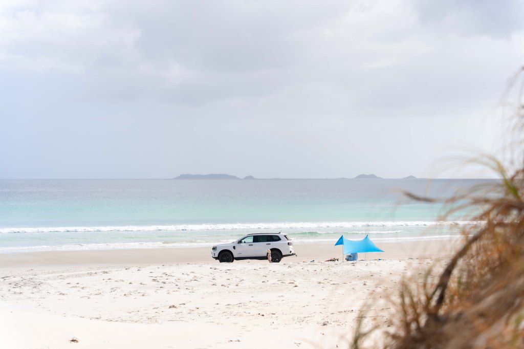 Ideal beach setup at Puwheke Beach on the Karikari Peninsula, Northland New Zealand — family sun tent, towels, and surfboard ready for a relaxed seaside day.