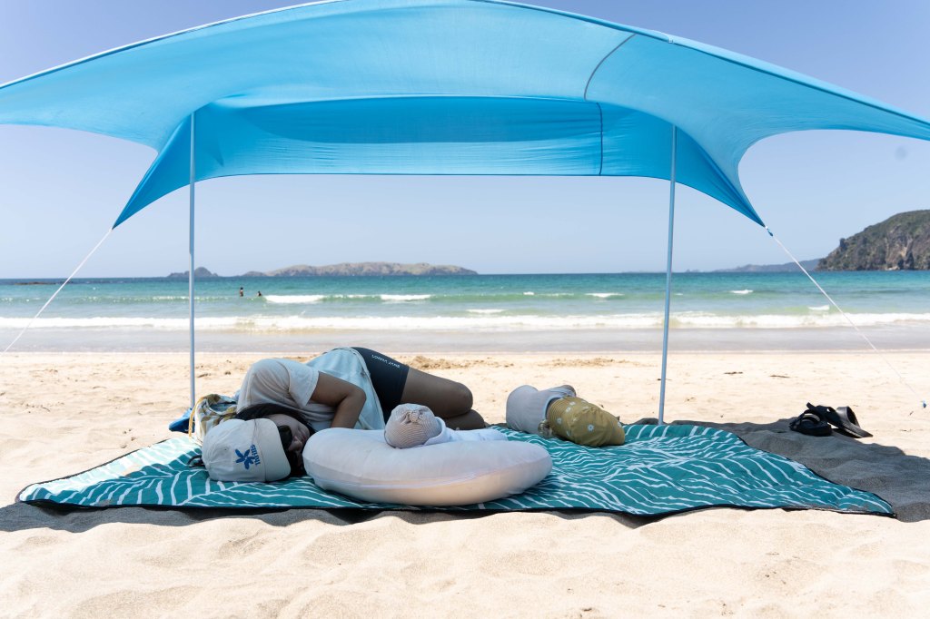 Bianca relaxing with her kids during nap time at the beach on the Karikari Peninsula, Northland New Zealand — peaceful family moment by the ocean.
