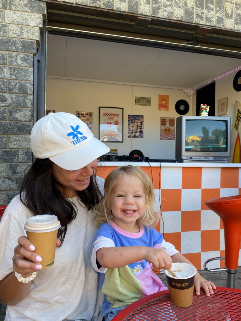 Florence enjoying a babycino at Salty Brew in Tokerau Beach, Karikari Peninsula — family-friendly coffee stop in Northland New Zealand before a day at the beach.